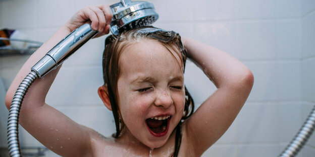 Ein Kind hält einen Duschkopf mit fließendem Wasser über seinen Kopf