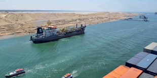 Frachtschiff und zwei kleinere Schiffe in einem Kanal in der Wüste