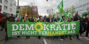 ein grünes Plakat "Demokratie ist nicht verhandelbar" wird getragen von einer Menschenkette