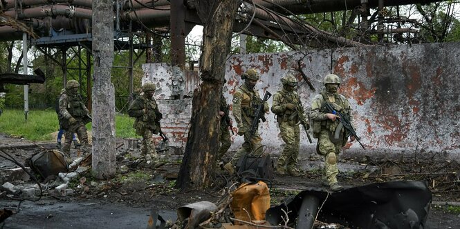 Mehrere Soldaten laufen durch ein verwüstetes Gebiet