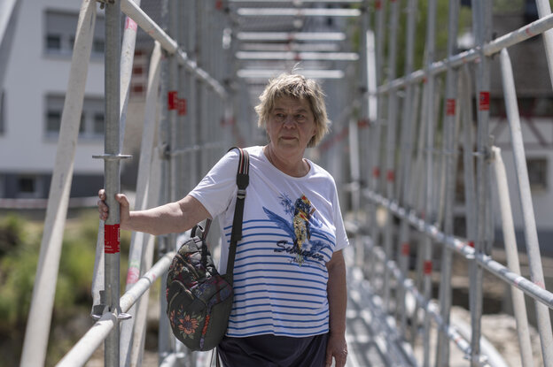 Eine Frau auf einem Stahlgerüst über einer alten Brücke