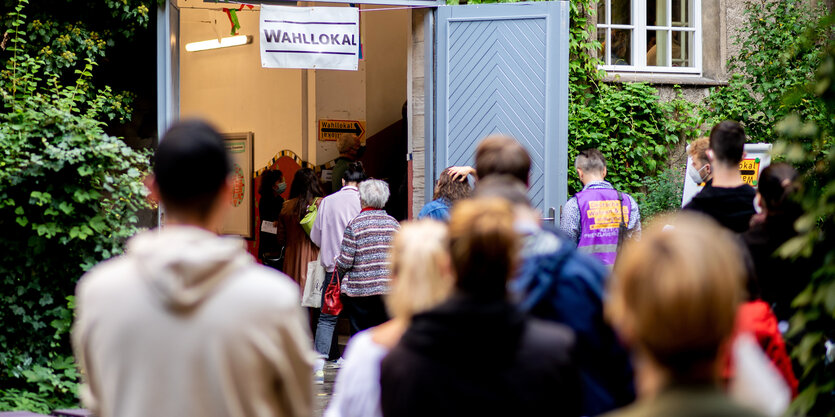 Menschen stehen Schlange vor einem Wahllokal