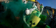 Aktivist*in in grünem Dampf hält Atomfass-Attrappe