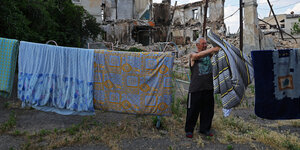 Ein Anwohner hängt Wäsche bei einem zerstötendd Wohnhaus auf