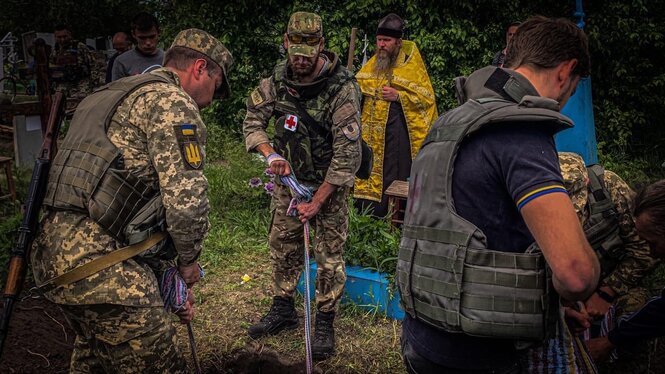 Ukrainische Soldaten vor einem Grab