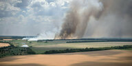 Rauch steigt hinter den Feldern von Bauern an den Frontlinien auf, an denen sich ukrainische und russische Truppen heftige Kämpfe liefern