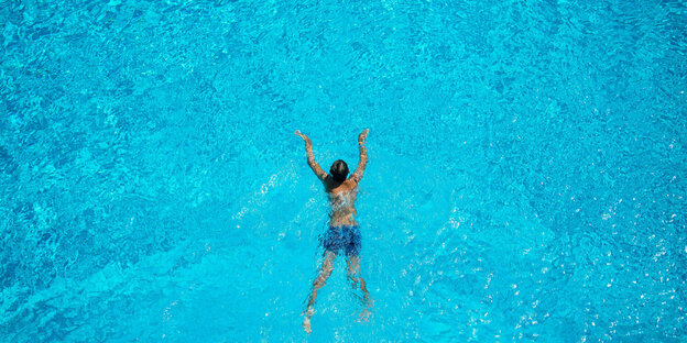 Eine Frau schwimmt im Freibad