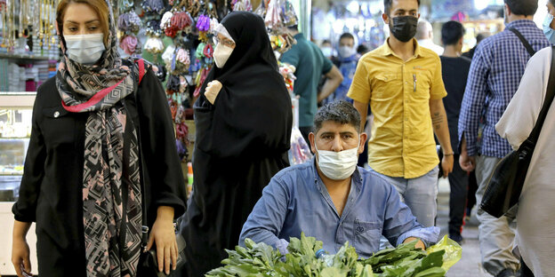 Menschen auf einem Markt in Teheran tragen Masken