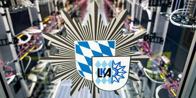 Logo LKA und Bayernwappen, dahinter unscharf ein Rechnerraum