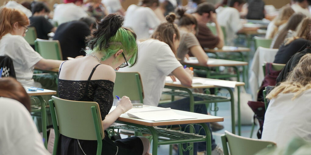 Schüler*innen von hinten an Einzelpulten, im Zentrum eine Person mit grünem Undercut.