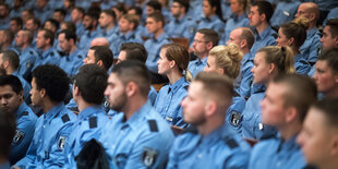 Viele Polizist*innen sitzen bei ihrer Vereidigung in einem Hörsaal