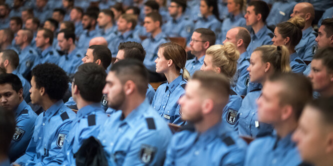 Viele Polizist*innen sitzen bei ihrer Vereidigung in einem Hörsaal