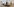 Installationsainsicht: Links im Bild hängt Franz Klekawas Gemälde „Treffpunkt Bahnhof“ (1973), an einer Säule lehnt eine Word Art-Arbeit von Joseph Kosuth, im Bildvordergrung sind in die Ausstellung transportierte Gehwegplatten auf dem Boden zu sehen, im Hintergrund ein umgebautes Lastenrad, das Adrien Missika zu einer Performance dient