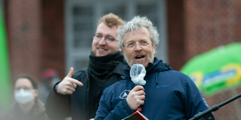 Ein junger Mann zeigt auf einen älteren Mann, der ein Mikrofon in der Hand hält