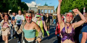 Menschen in bunten Kostümen tanzen vor dem Brandenburger Tor