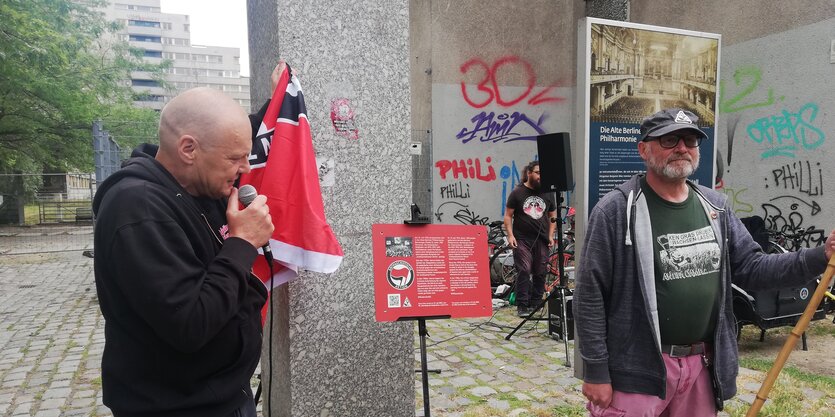 Bernd Langer zieht eine Antifafahne von einer Infortafel