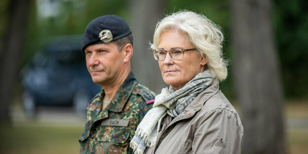 Ein Soldat steht hinter blonder Frau mit Brille