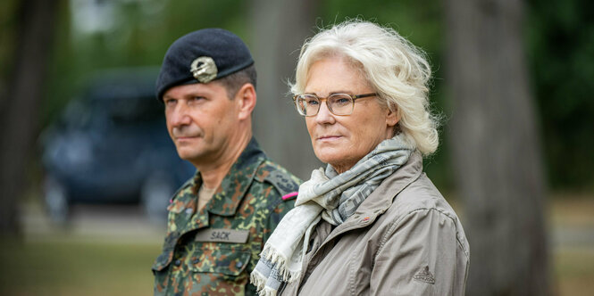 Ein Soldat steht hinter blonder Frau mit Brille