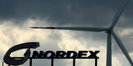 Über das Rotorblattwerk des Windkraftanlagen-Herstellers Nordex ziehen dunkle Wolken hinweg, eine Windkraftanlage auf dem Betriebsgelände dreht sich