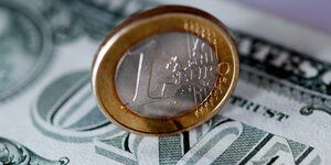 Eine Ein-Euro-Münze steht auf einem Ein-Dollar-Schein. Der Eurokurs ist erstmals seit fast 20 Jahren auf ein Dollar-Tauschverhältnis von eins zu eins gefallen.