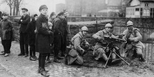 Französische Soldaten im Jahr 1923 an einem Maschinengewehrposten, daneben Zivilisten