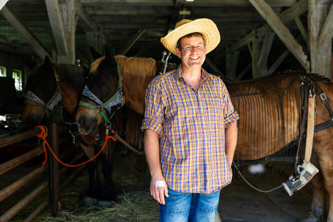 Jan Sommer mit Strohhut vor Pferden stehend