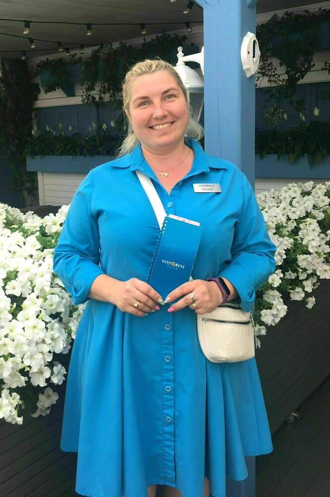 Oksana steht in blauem Kleid vor einer Terrasse