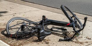 Ein beschädigtes Elektrofahrrad liegt am straßenrand