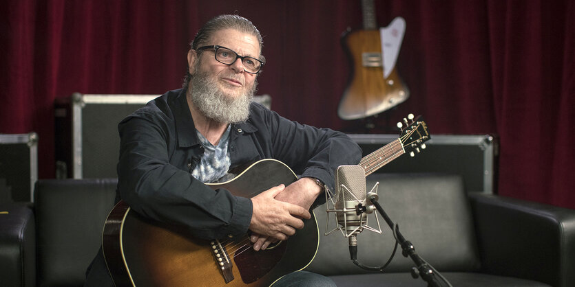 Gustavo Santaolalla sitzt an seinem Hauptinstrument, der Gitarre.