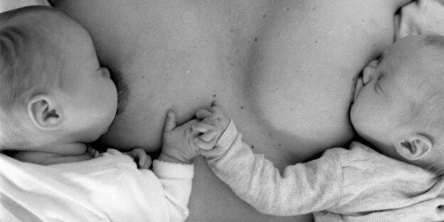 Zwei Säuglinge hängen an der Brust der Mutter