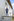 Ein Mann steht auf einer Mauer, dahinter ein weiß gestrichenes zweistöckiges Haus