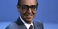 Ein Mann mit Brille vor blauem Hintergrund