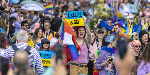 Menschen auf einer Pride-Parade. Eine Person zeigt ein Schild „Ukraine is gay“.