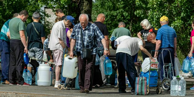Eine Gruppe von Menschen holt sich Wasser in Kanistern