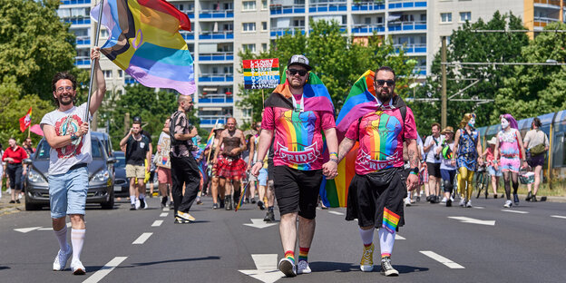 Teilnehmer der Pride Parade in Berlin-Marzahn im Juni 2022, sie tragen Regenbogenfahnen