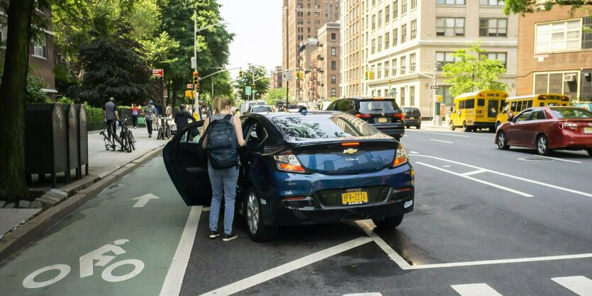 Eine Frau mit Rucksack steigt in ein Auto