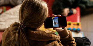 Eine junge Frau guckt auf ein Smartphone