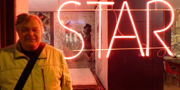 Der Berliner Musiker Klaus Beyer vor einem Schaufenster mit "Star"-Leuchtschrift