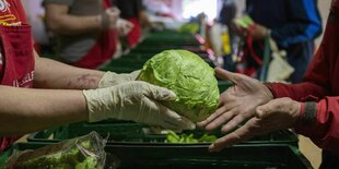 Eine Mitarbeiterin übergibt einer Person einen Eisberg Salat