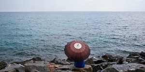 Ein Mann hinter einem Regenschirm an der Küste