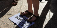 Jemand steht mit den Füssen auf einem Protestplaktat auf dem zu lesen ist " BANS OF OUR BODIES"