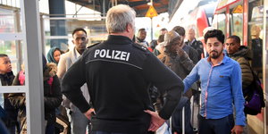 Ein Beamter der Bundespolizei kontrolliert Reisende auf dem Bahnsteig
