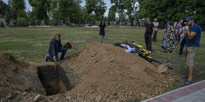 Menschen stehen am offenen Grab eines getöteten Soldaten.
