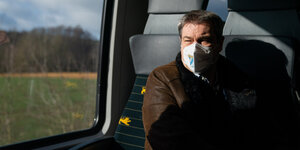Markus Söder mit Maske in einem Zugabteil