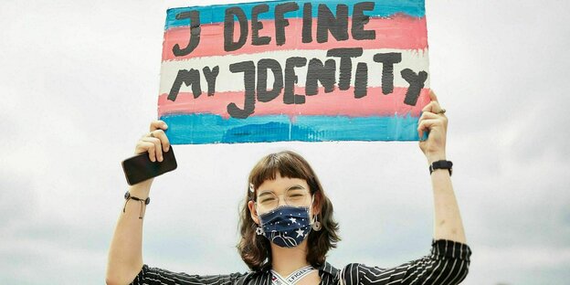 Eine Demonstrantin hält ein Schild mit dem Slogan "I Define my identity" hoch