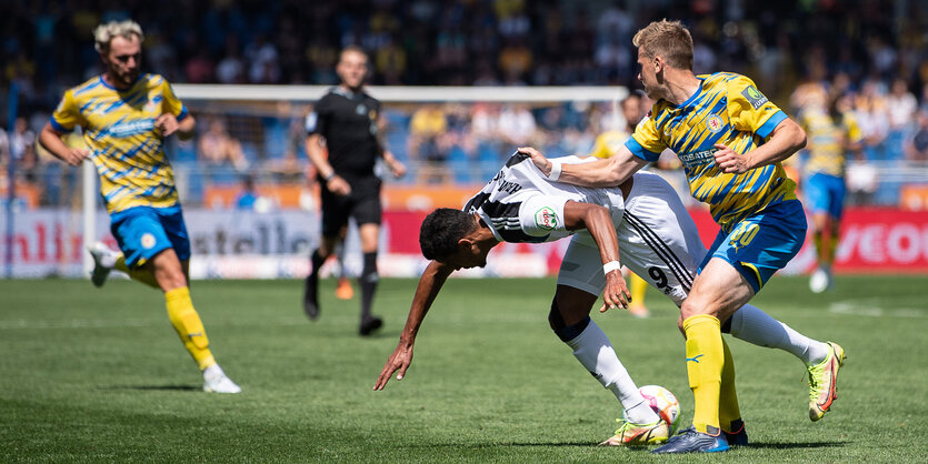 Braunschweigs Brian Behrendt zieht Hamburgs Robert Glatzel bei einem Zweikampf am Trikot.