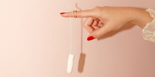 Eine Frau hält einen frischen Tampon in der Hand