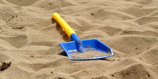 Eine Kinderschaufel liegt im Sand