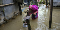 Eine Frau versucht an einer Pumpe Wasser in einem Gefäß zu sammeln