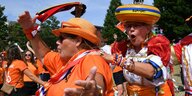Zwei Fans der Niederlande, eine mit eionem Goudakäse auf dem Kopf, tanzen auf der Straße